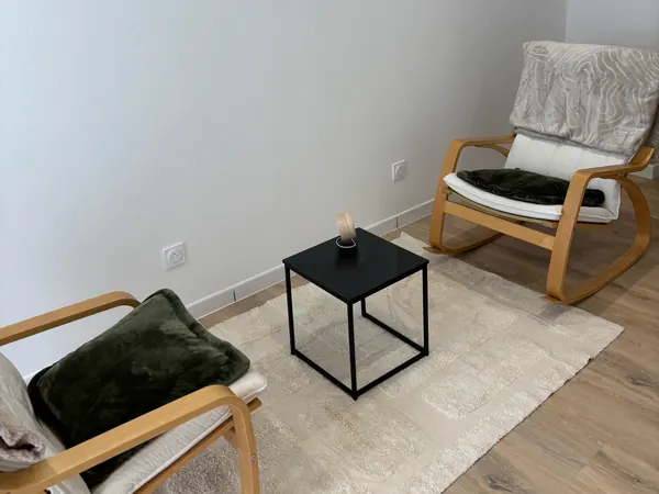Pièce avec deux fauteuils à bascule, une table d'appoint noire et un tapis